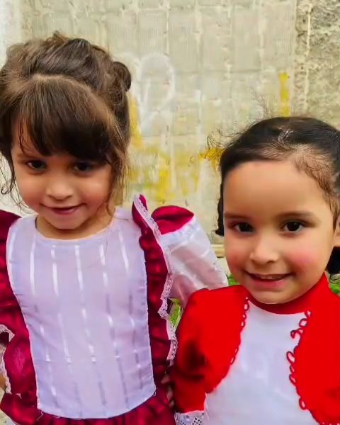Duas meninas vestidas de prenda sorrindo