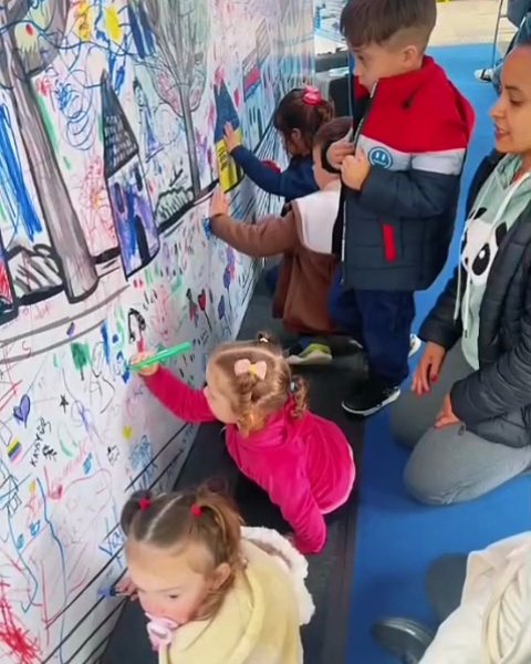 Crianças desenhando num grande mural de papel na Feira do Livro