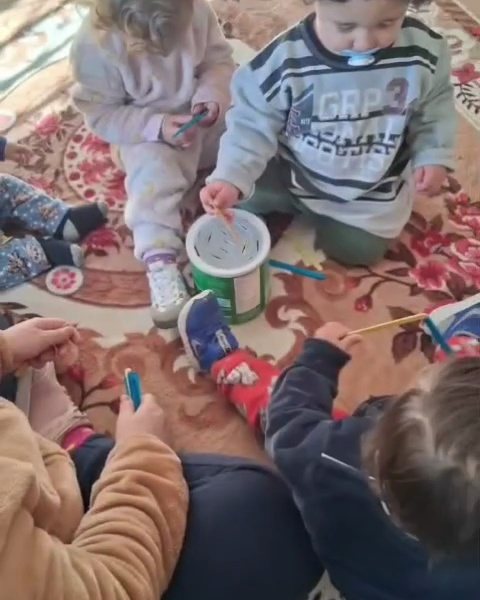 Crianças no tapete brincando com tiras de papel verde e amarelo