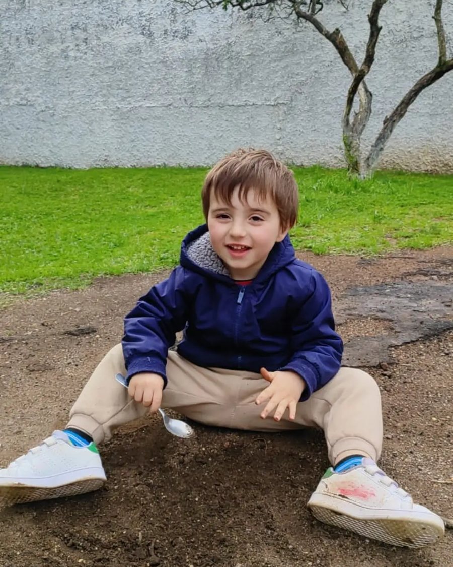 Menino sentado na terra do pátio, sorrindo